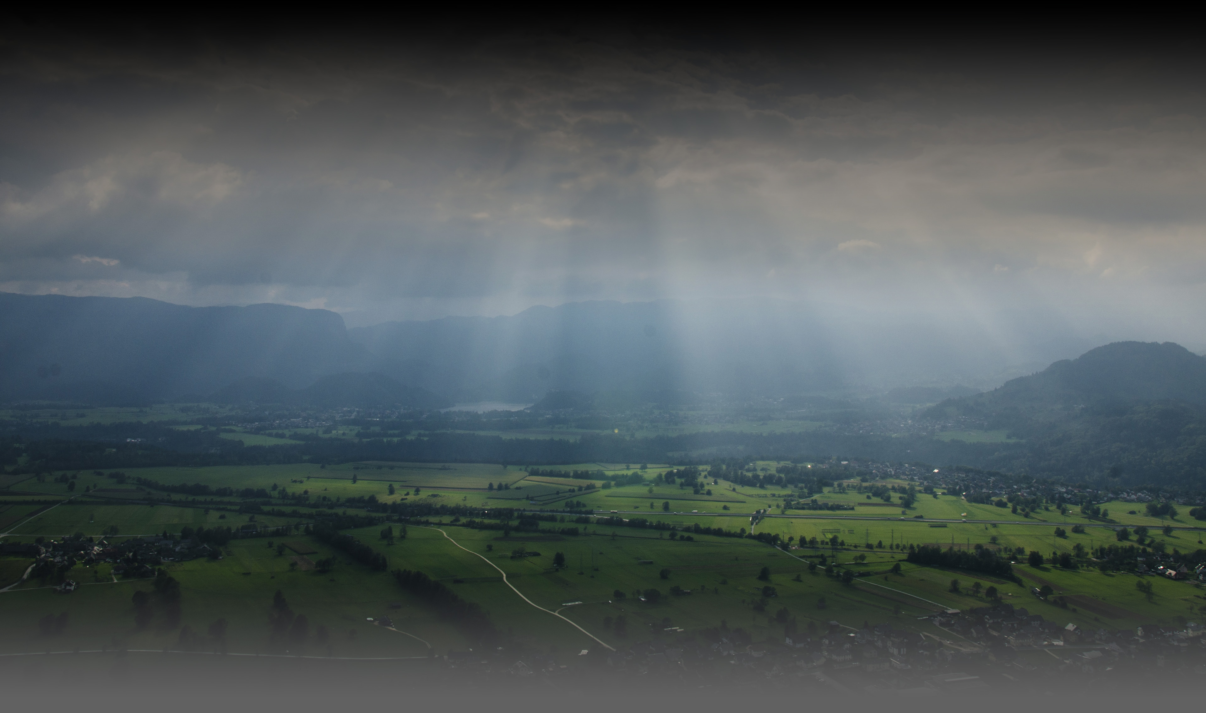Sun filtering through clouds over a green valley
