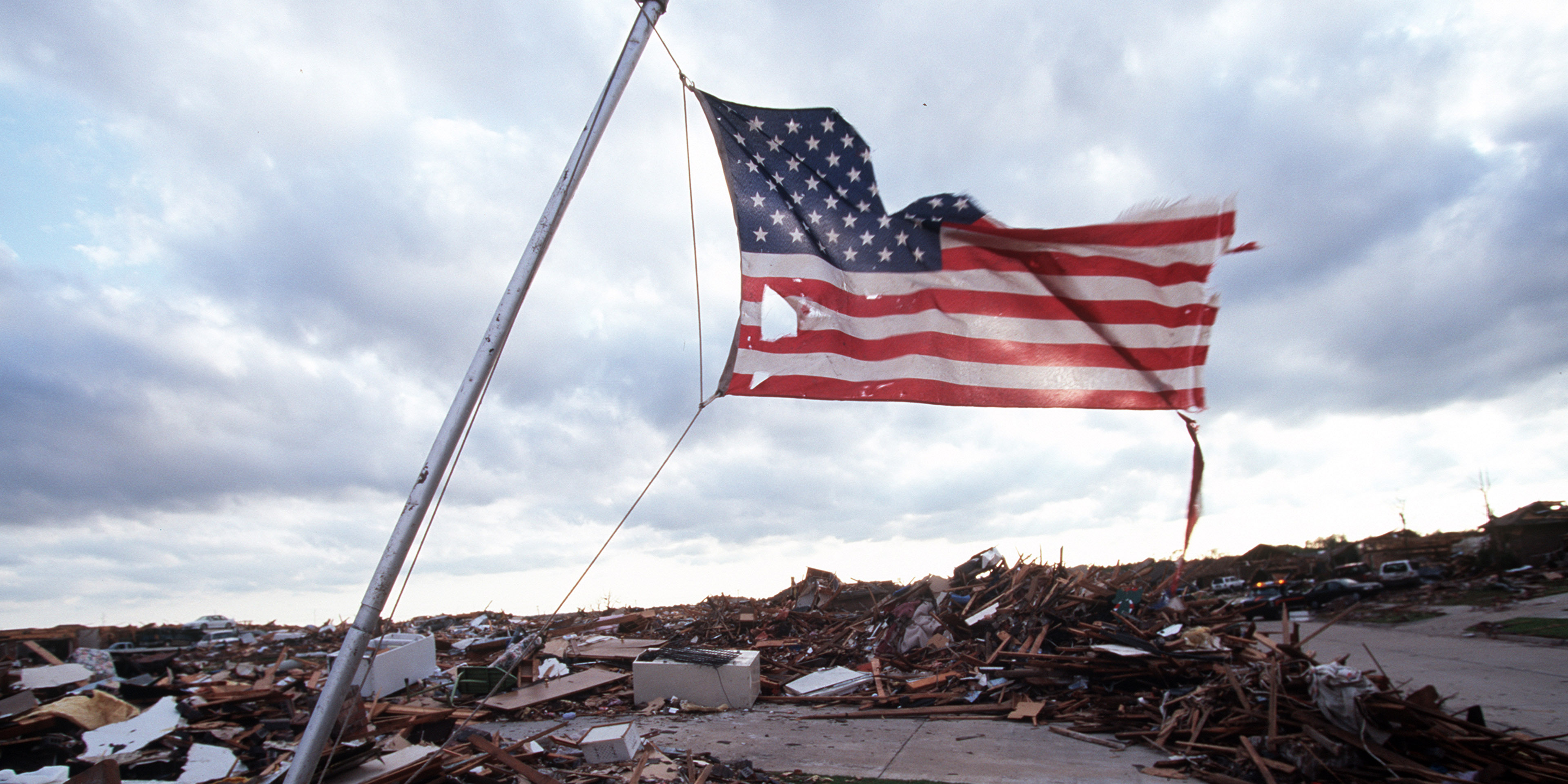 Tattered American flag flies over area devastated by tornado