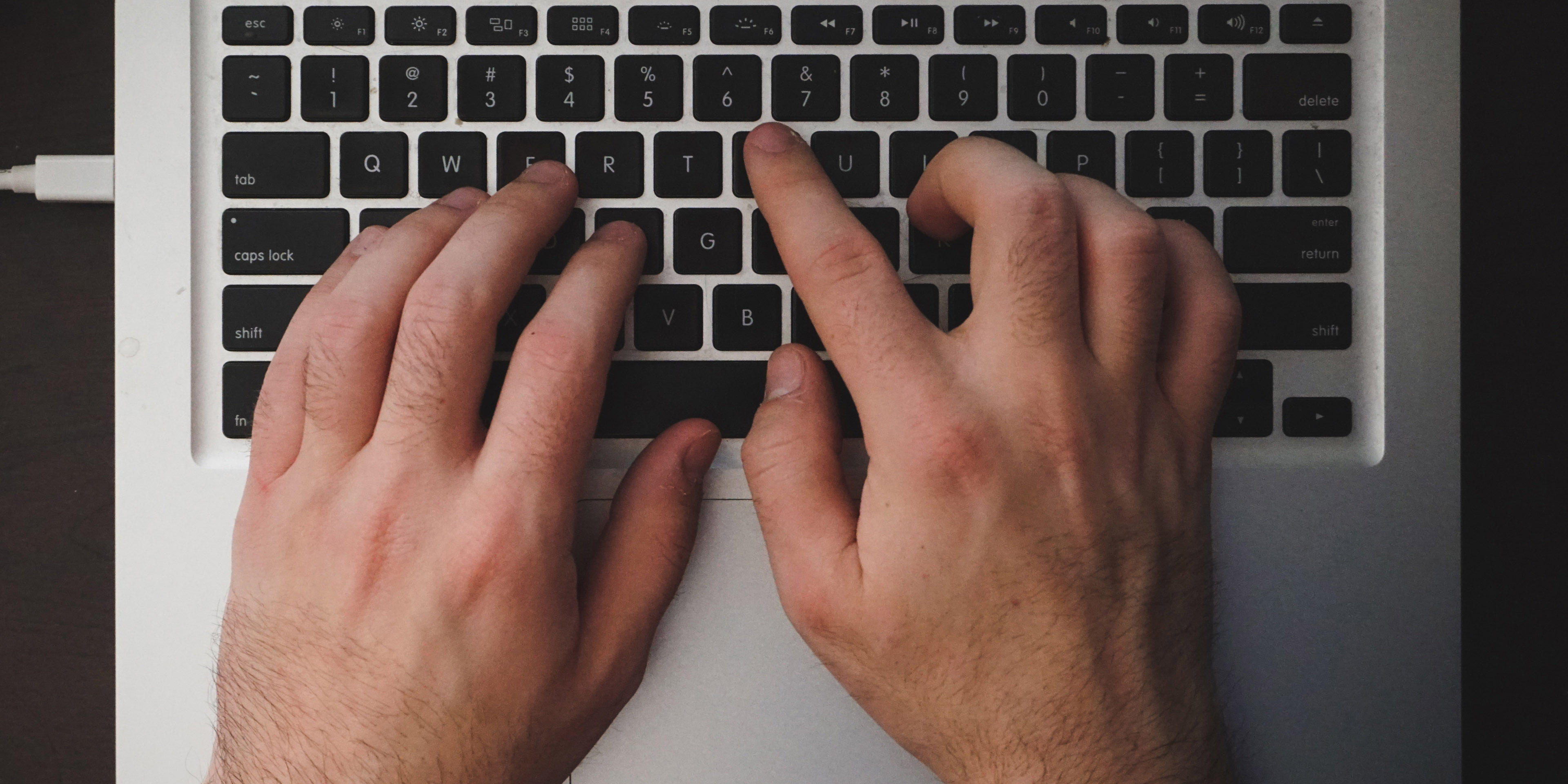 A pair of hands typing on a laptop keyboard.