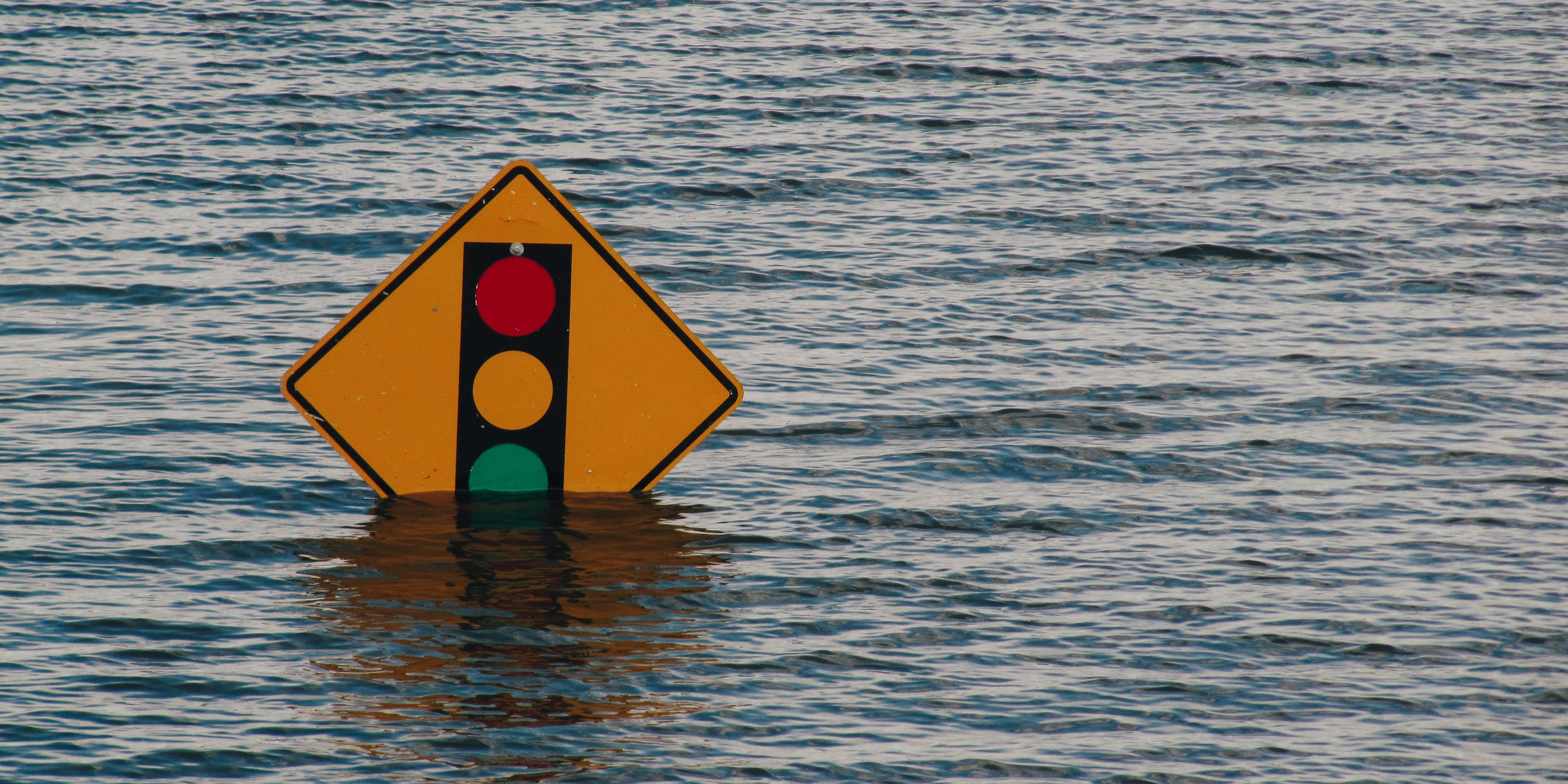A traffic light street sign in high flood water.
